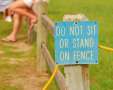 Do,not,sit,on,fence,sign,with,fence,sitters,in