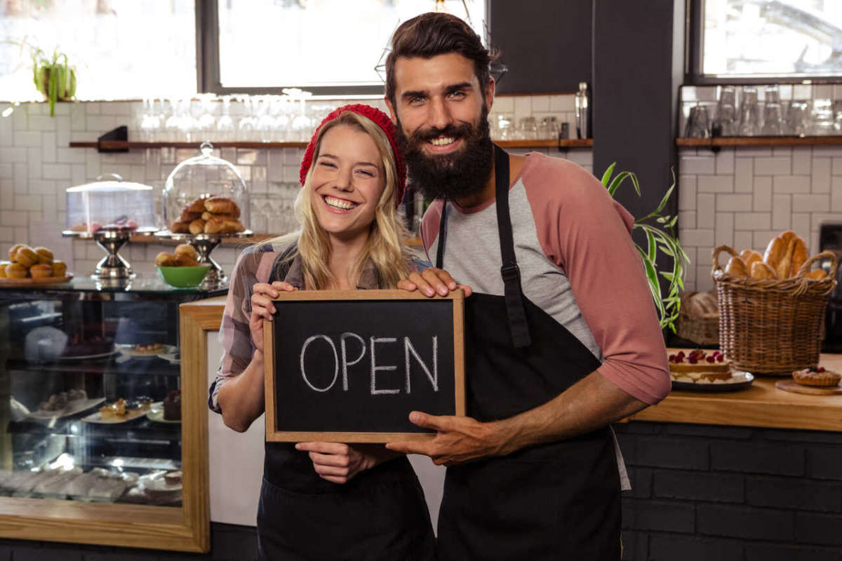 Waiter,holding,blackboard,with,open,in,the,cafe