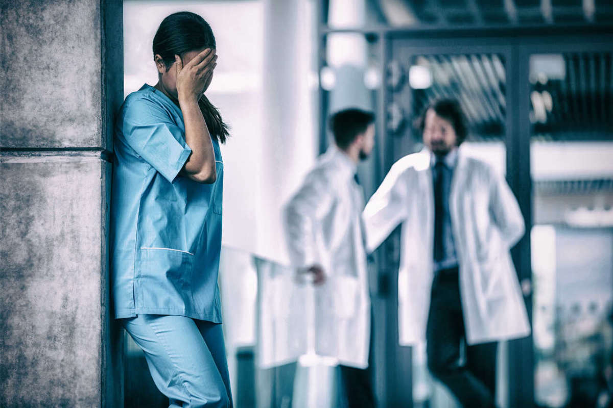 Stressed,nurse,standing,against,wall,in,hospital