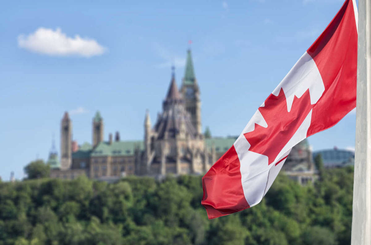 Canadian,flag,waving,with,parliament,buildings,hill,and,library,in