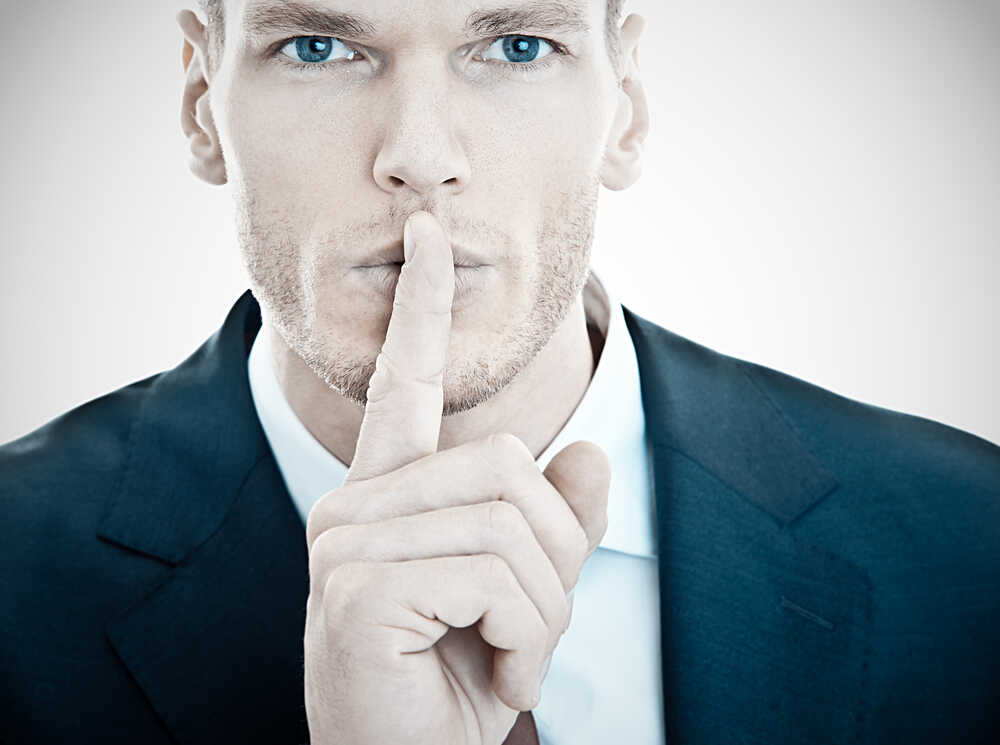 Businessman,with,finger,on,lips,asking,for,silence