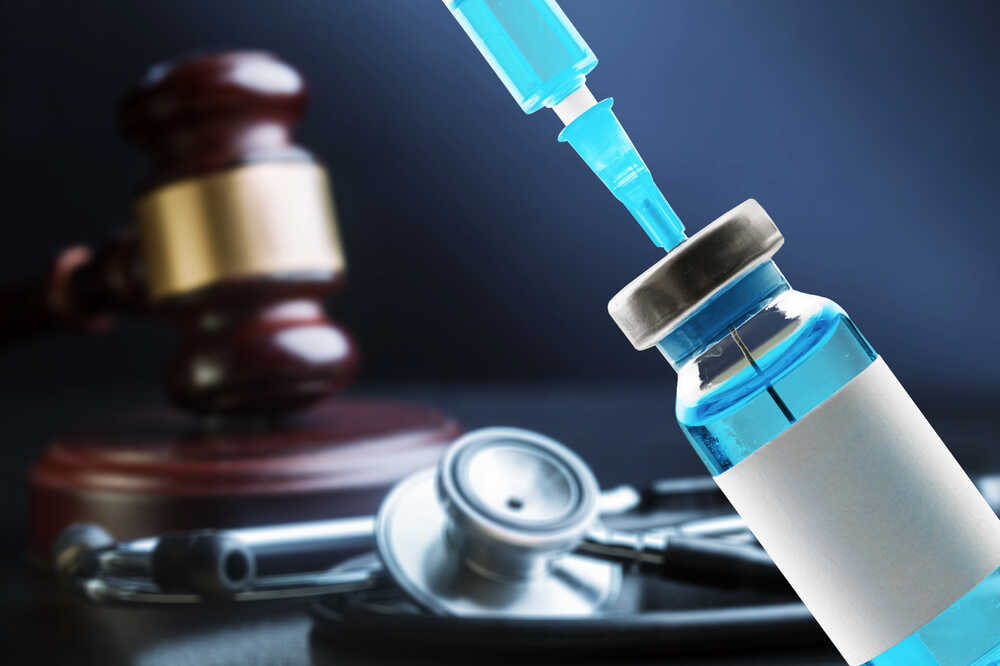 Law,and,vaccination,concept.,bottle,of,covid 19,vaccine,,gavel.